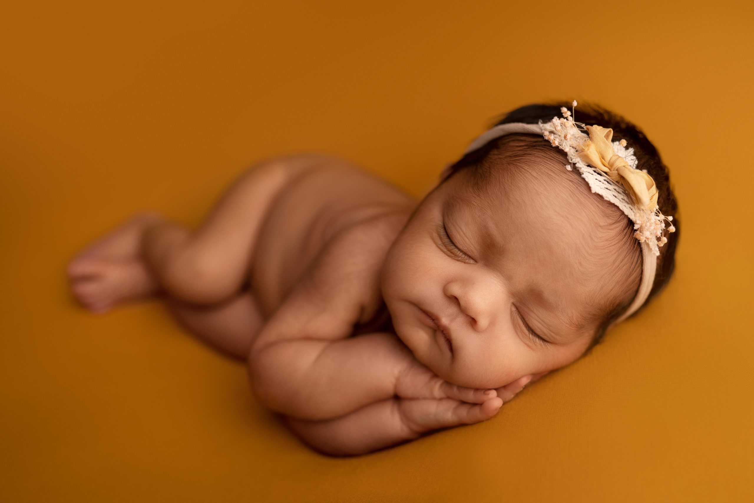 Indian newborn baby on mustard coloured backdrop